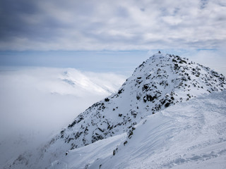 Fototapeta na wymiar Highest points of Low Tatras - Chopok peak and Dumbier peak (Slovakia). Beautiful winter mountains landscape above the clouds.