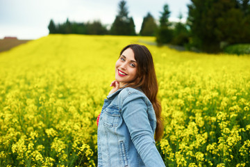 Naklejka na ściany i meble A young caucasian woman in rapeseed field