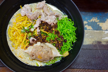 Tom Yum Kung with noodles and seafood in black bowl