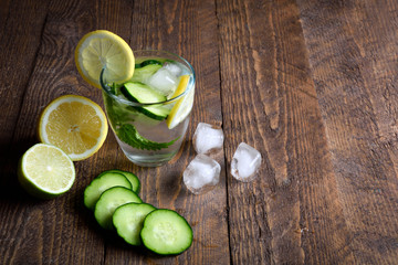 Water with lemon,lime  mint and cucumber on the wooden dark background. Water Detox.on wooden background