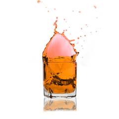 orange cocktail splashing on a glass on white background