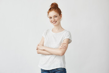 Portrait of young redhead girl smiling with crossed arms.