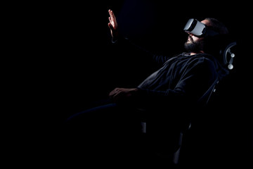 Young hipster bearded man wearing virtual reality goggles. Black background studio VR concept