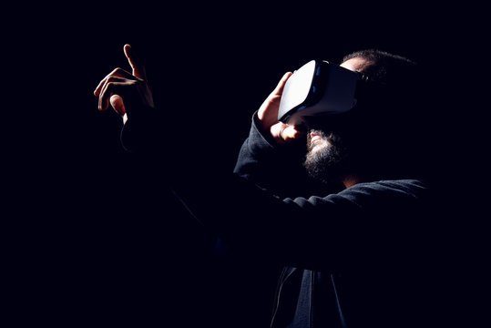 Fototapeta Young hipster bearded man wearing virtual reality goggles. Black background studio VR concept