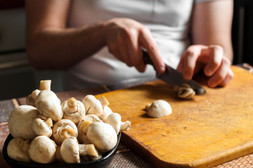 man cutting mushrooms on wooden cutting board