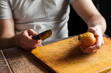 Man cleans a knife and cut the onion