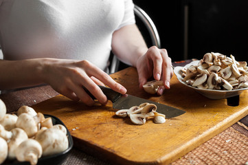 man cutting mushrooms on wooden cutting board