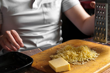 cooking, food and home concept - close up of male hands grating cheese