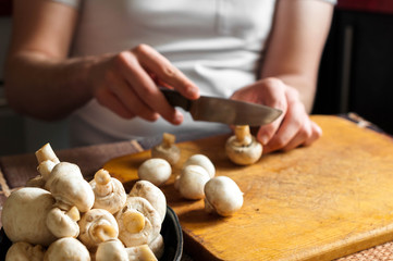 man cutting mushrooms on wooden cutting board