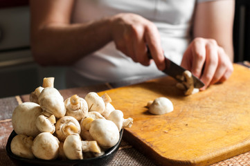 man cutting mushrooms on wooden cutting board