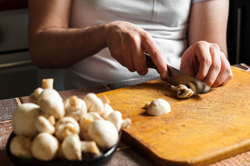 man cutting mushrooms on wooden cutting board
