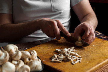 man cutting mushrooms on wooden cutting board