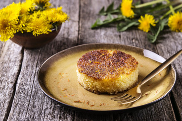 Pieces of simple homemade semolina sponge cake with saffron on vintage wooden table decorated dandelions. Selective focus 