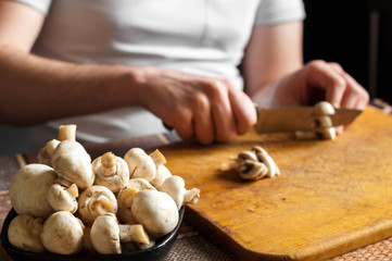 man cutting mushrooms on wooden cutting board