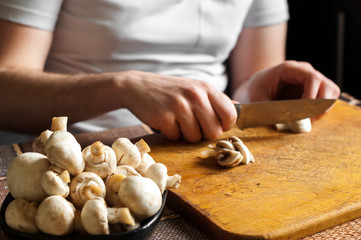 man cutting mushrooms on wooden cutting board