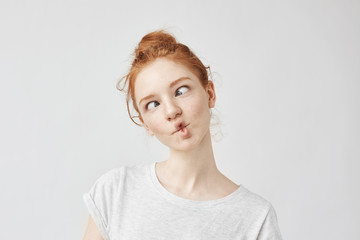 Portrait of funny cute ginger girl with freckles fooling.