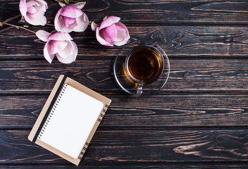 Flower magnolia and cup of black tea