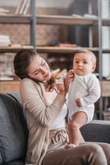 Portrait of cheerful woman talking on smartphone and spending time with her son at home