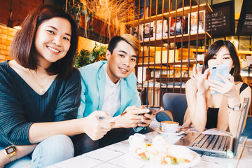 Young men and women sitting at cafe table for business talking with laptop