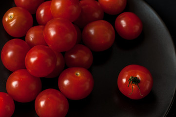 full top view of pile of cherry tomatoes in a rattan basket on black board for background