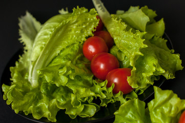 Healthy vegetarian Salad cherry tomatoes and lettuce on the black plate