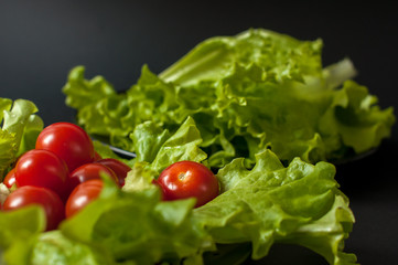 Healthy vegetarian Salad cherry tomatoes and lettuce on the black plate