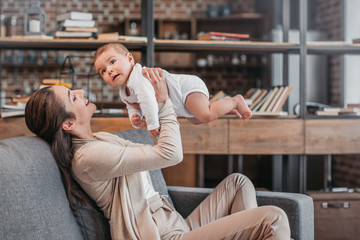 Side view of cheerful mother and baby boy having fun together at home
