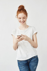 Fototapeta premium Attractive redhead girl with freckles smiling looking at phone.