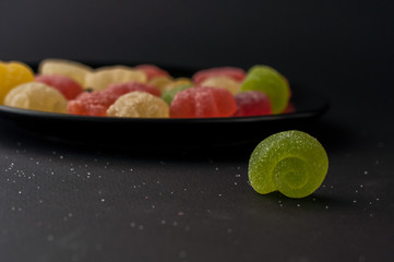 Colorful jelly candies on a black plate background.