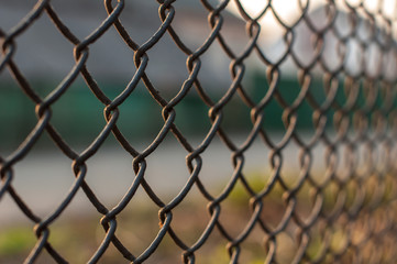 Fototapeta premium Sunset view over the city through the wire mesh fence, close up shot