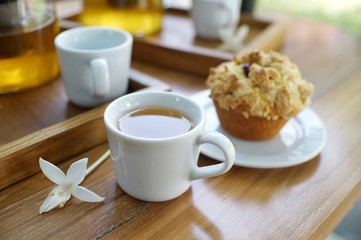 A cup of tea with muffin on wooden table 