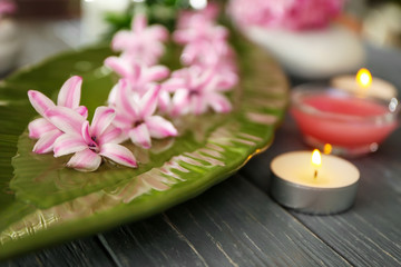 Beautiful spa composition of plate with flowers and candle on table