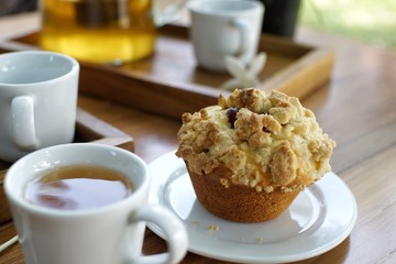Muffin with a cup of tea on wooden table in the garden