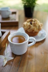 A cup of tea with muffin on wooden table in the garden