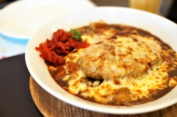A dish of Hamburg curry rice roasted with cheese on top seen on the table