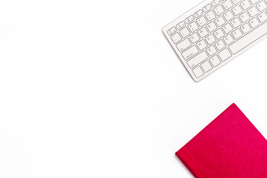 Pink diary and keyboard on a white background. Minimal feminine business concept.