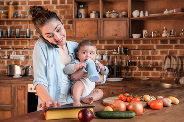 Mother with her baby son looking for recipe on digital tablet before cooking dinner in the kitchen