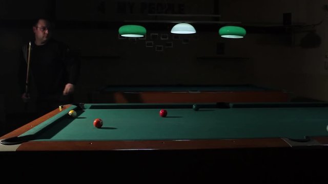 Man performs trick billiards shot and throws pink ball in the middle hole. American billiard, 9-ball, nine-ball pool.