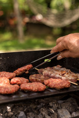 Grilled shish kebab and meat balls on barbecue at picnic also on background there are picnic table and hammock in frame