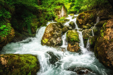 Jungle landscape with flowing turquoise water of georgian cascade waterfall at deep green forest. Mountain of georgia