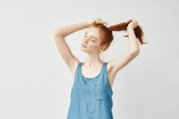 Obraz na płótnie Canvas Young beautiful redhead girl correcting her haircut.