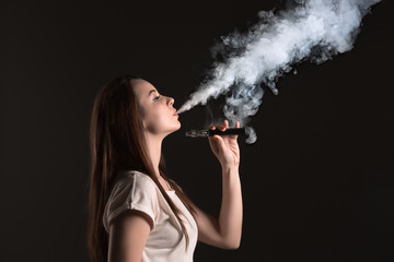 Fototapeta premium The face of vaping young woman at black studio