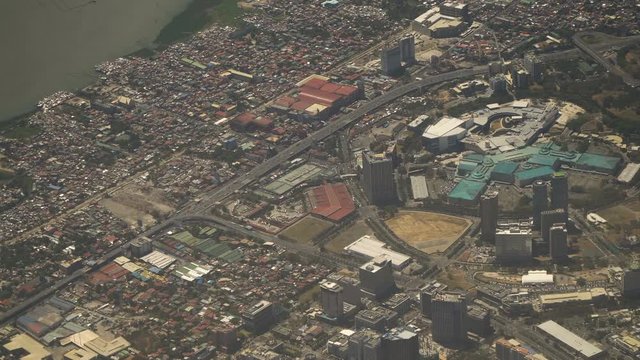 View through an airplane window on the city. Airplane window view showing wing of a plane flying over Manila. Aerial footage, 4K video, Philippines. Travel concept.