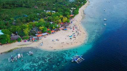 Naklejka premium Aerial view of sandy beach with tourists swimming in beautiful clear sea water of the Sumilon island beach landing near Oslob, Cebu, Philippines. - Boost up color Processing.