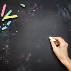 Female hand writing on a blackboard tabletop with white chalk © Neven Krcmarek