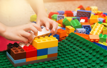 Close up of child's hands playing with colorful plastic blocks. Preschooler child playing with colorful toy blocks. Preschool children build tower with plastic block. Toddler kid in nursery.