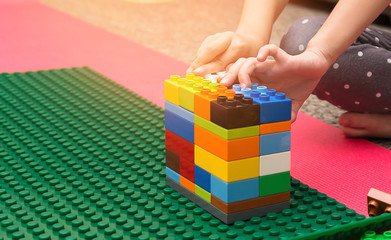 Close up of child's hands playing with colorful plastic blocks. Preschooler child playing with...