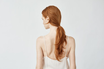 Fototapeta premium Portrait of redhead girl posing back turning face to camera.