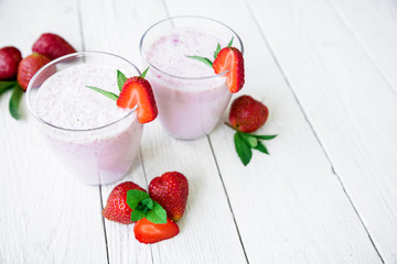 Fresh milkshake. Blueberry smoothie with strawberry on white wooden background. Flat lay. Top view