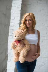 Lovely pregnant girl with a teddy bear.
